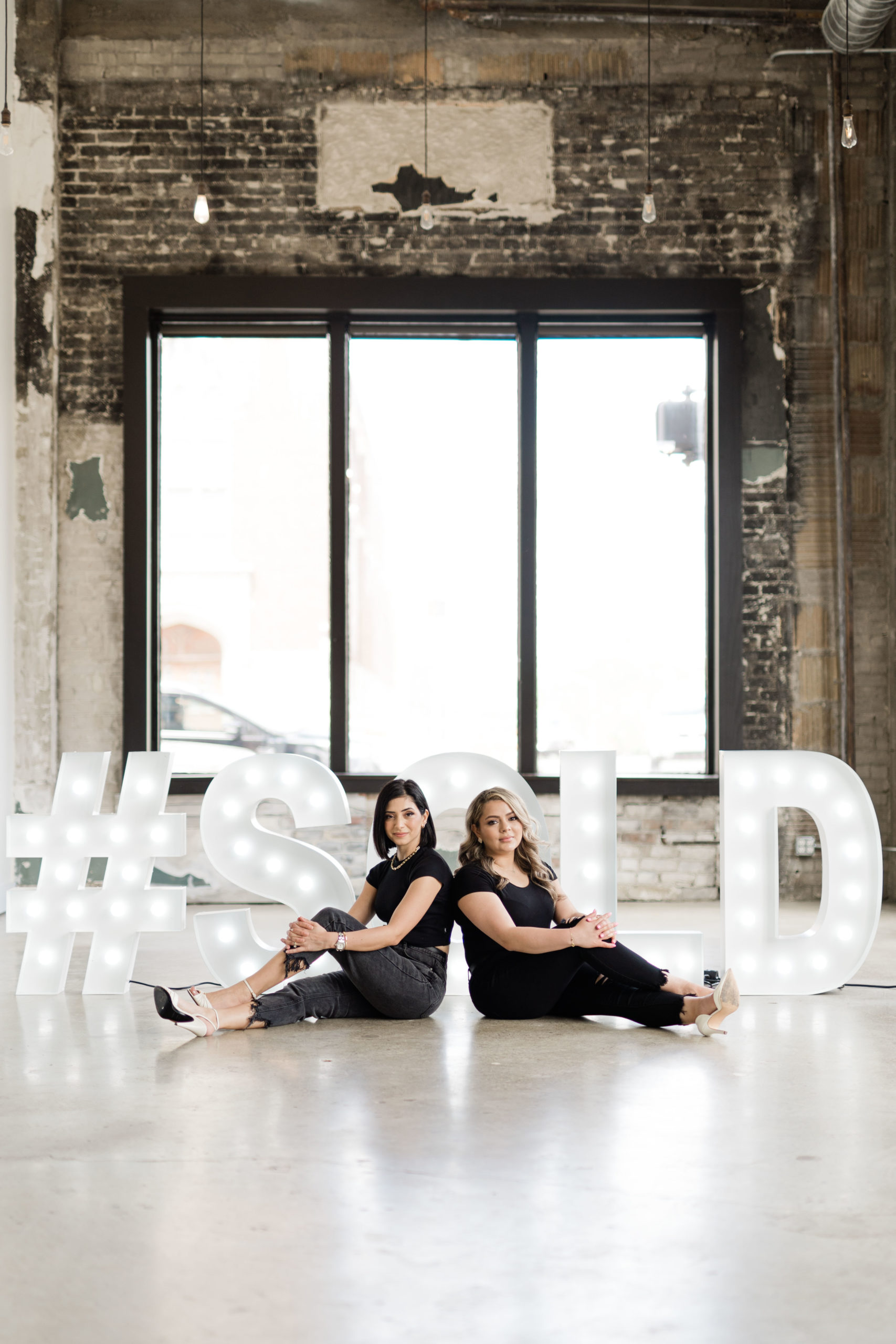 Two ladies sitting in front of marque light letters